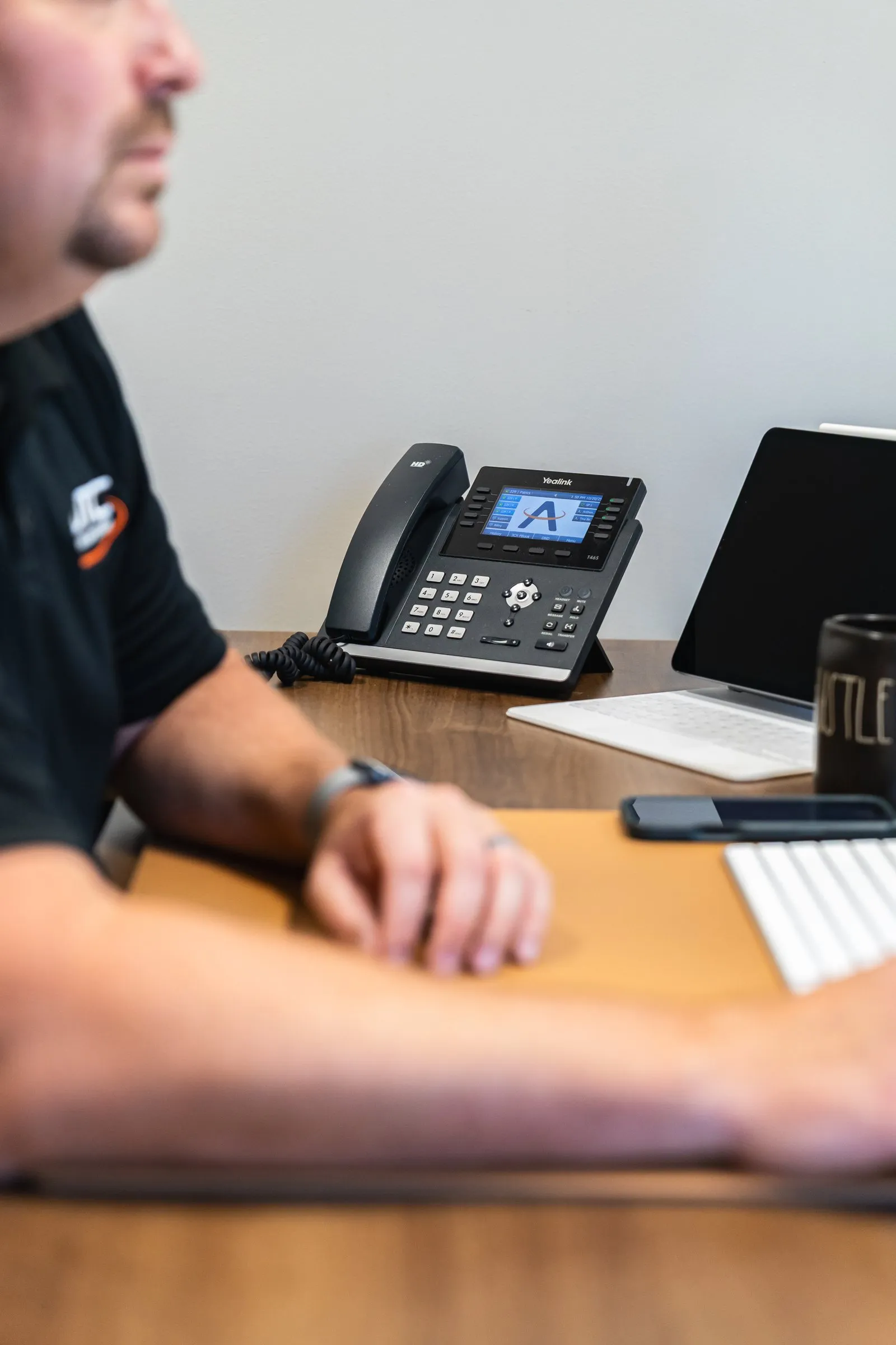 AJTC team member at a desk with a business VoIP phone